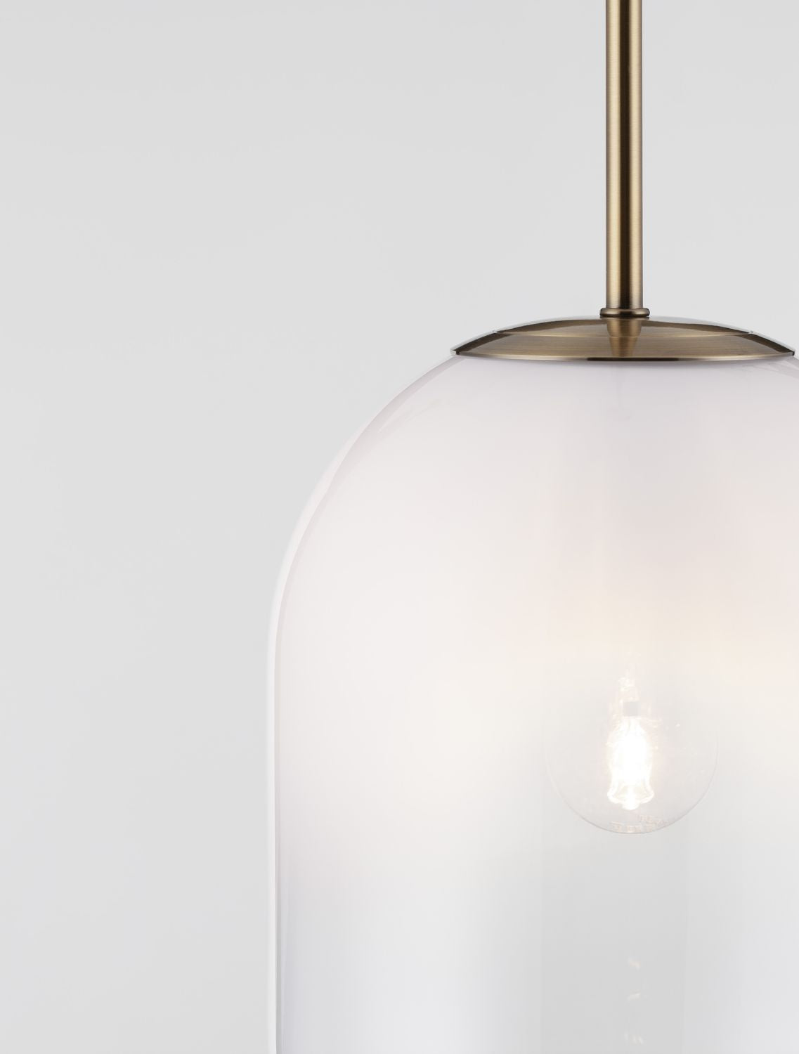 Gros plan sur la fixation dorée et le sommet du diffuseur en verre translucide.