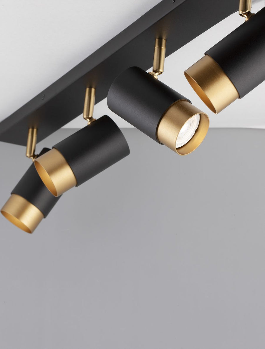 Détail en contre-plongée de trois spots cylindriques noirs et leurs embouts dorés.