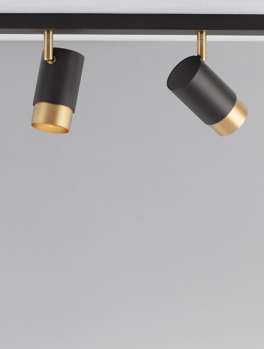 Vue rapprochée de deux projecteurs noirs orientables suspendus à leur rail plat.