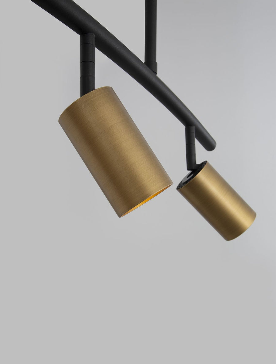 Détail de la finition brossée dorée et de l'articulation noire d'un projecteur.