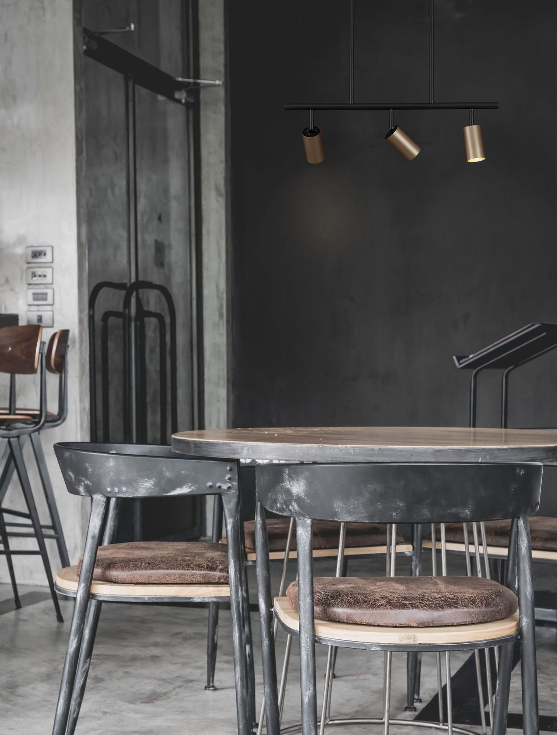 Mise en ambiance dans un café, suspension noire et dorée au-dessus d'une table