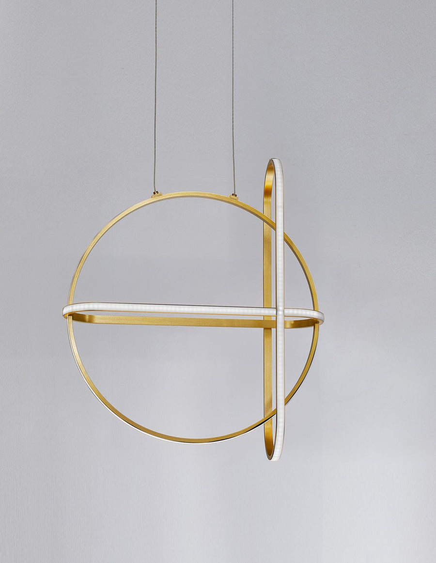Luminaire suspendu vu de trois quarts, anneaux dorés superposés sur fond gris clair