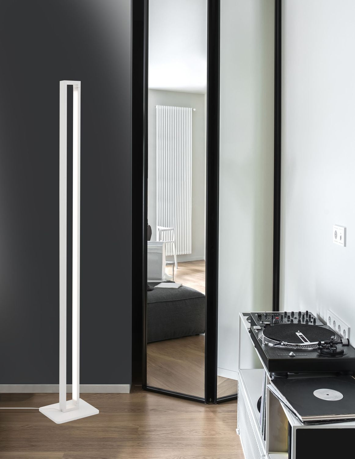 Lampadaire blanc vertical installé près d'un miroir, avec platine vinyle à droite