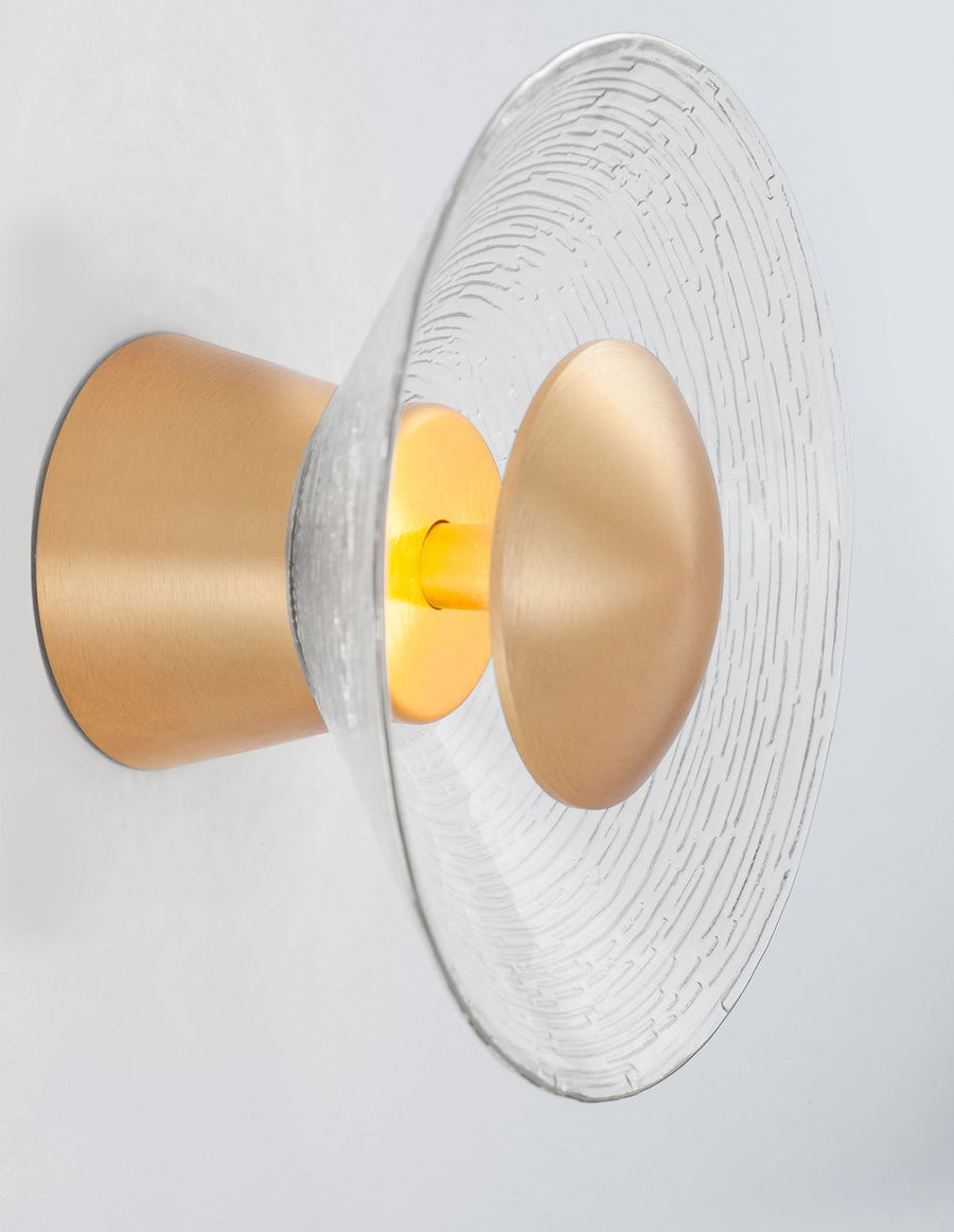 Détail de profil montrant le verre strié, le support doré et l'ampoule allumée.