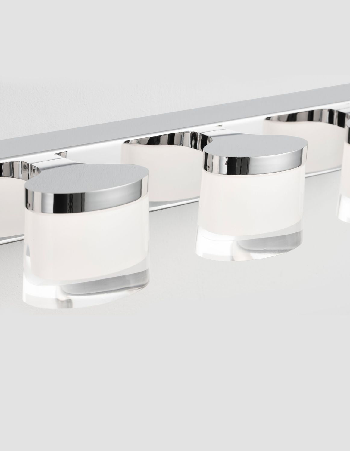 Détail rapproché des coupelles chromées et des verres blancs translucides du luminaire