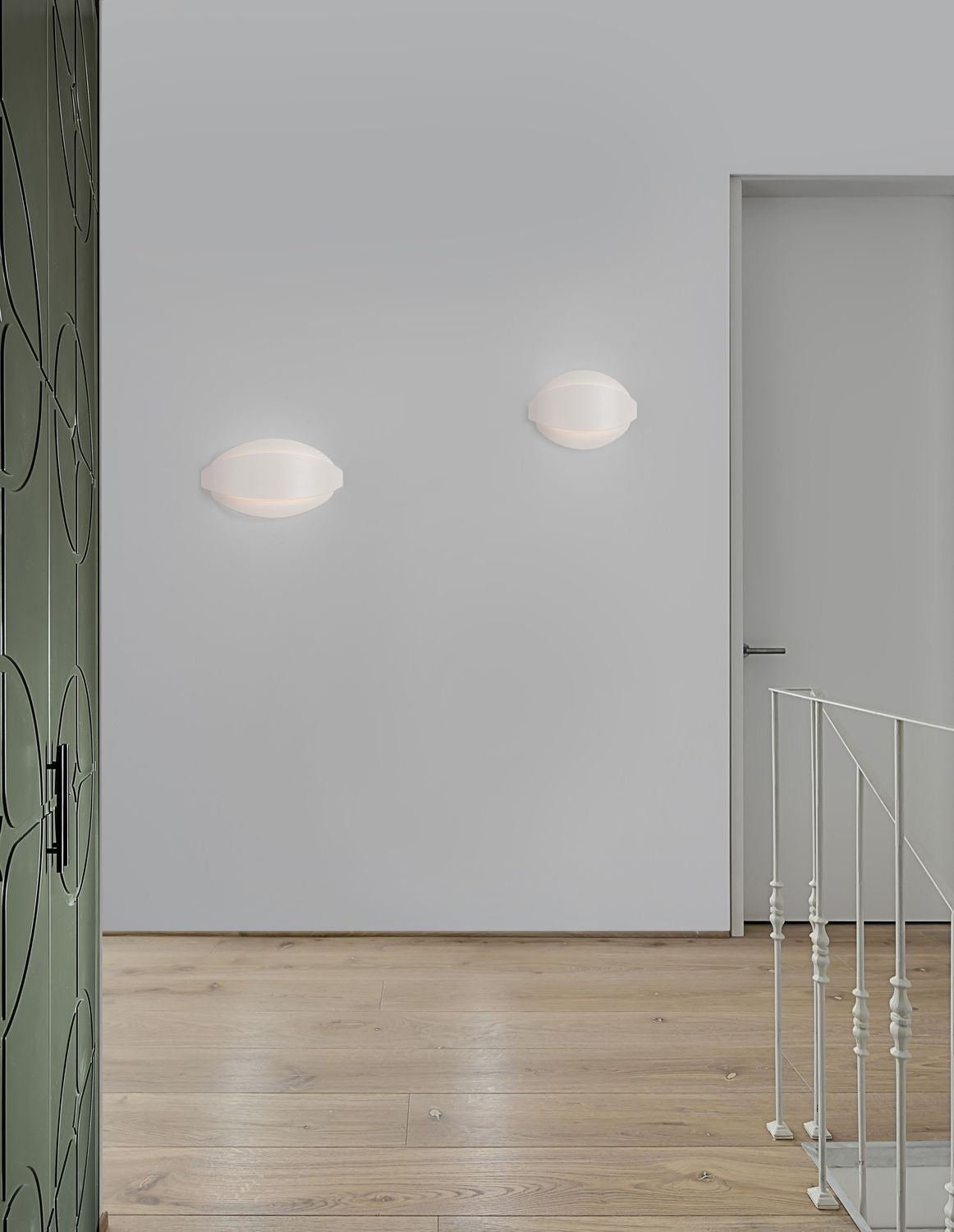 Deux appliques blanches ovales fixées sur un mur gris clair, en mise en ambiance