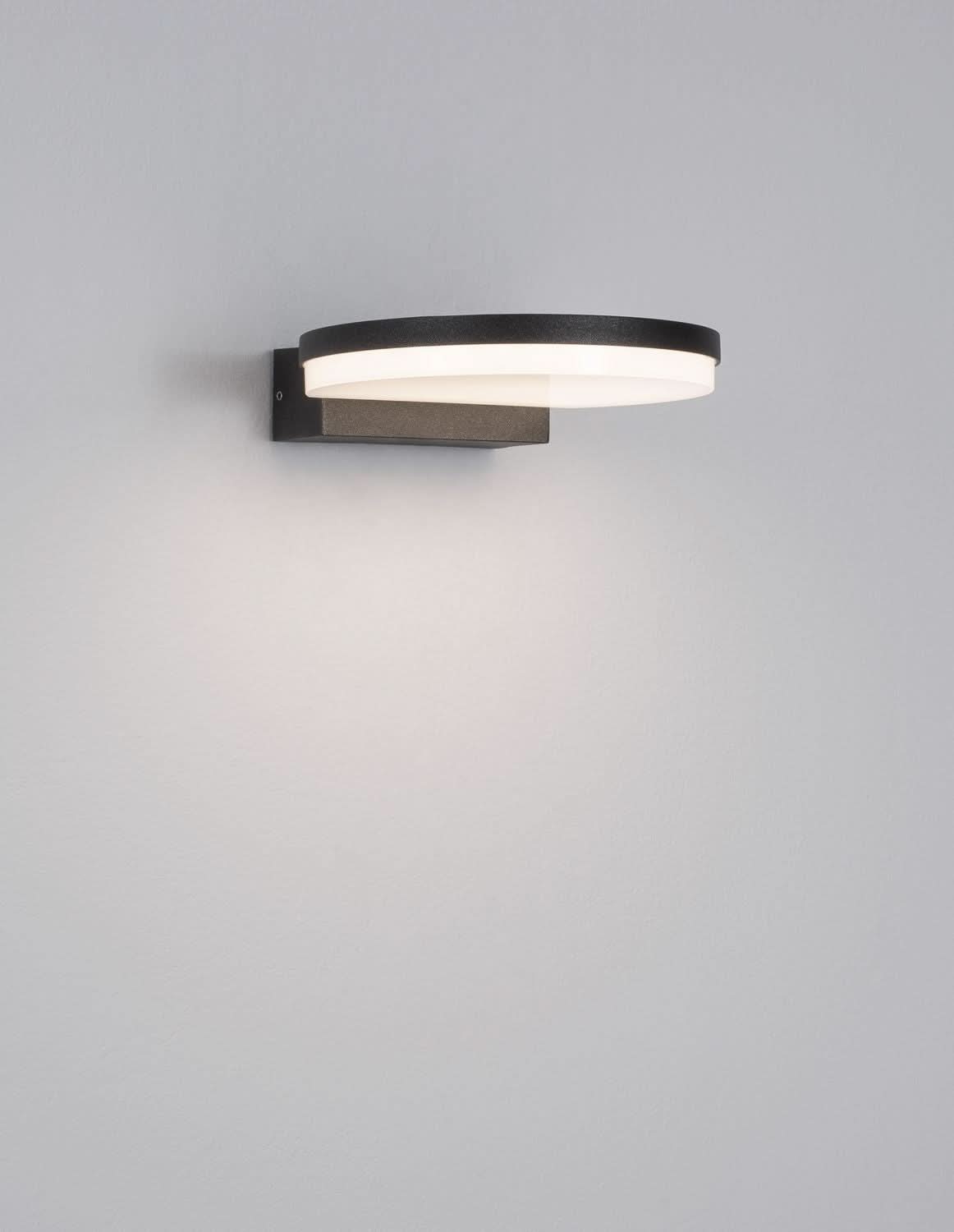 Applique murale allumée sur mur gris clair, halo lumineux diffusé vers le bas