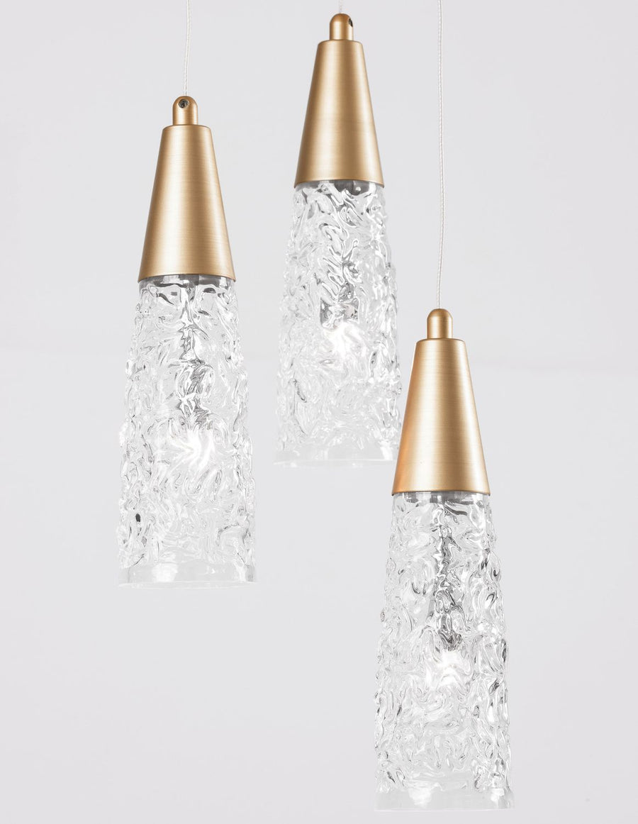 Détail rapproché des trois cônes dorés et abat-jours en verre moulé transparent