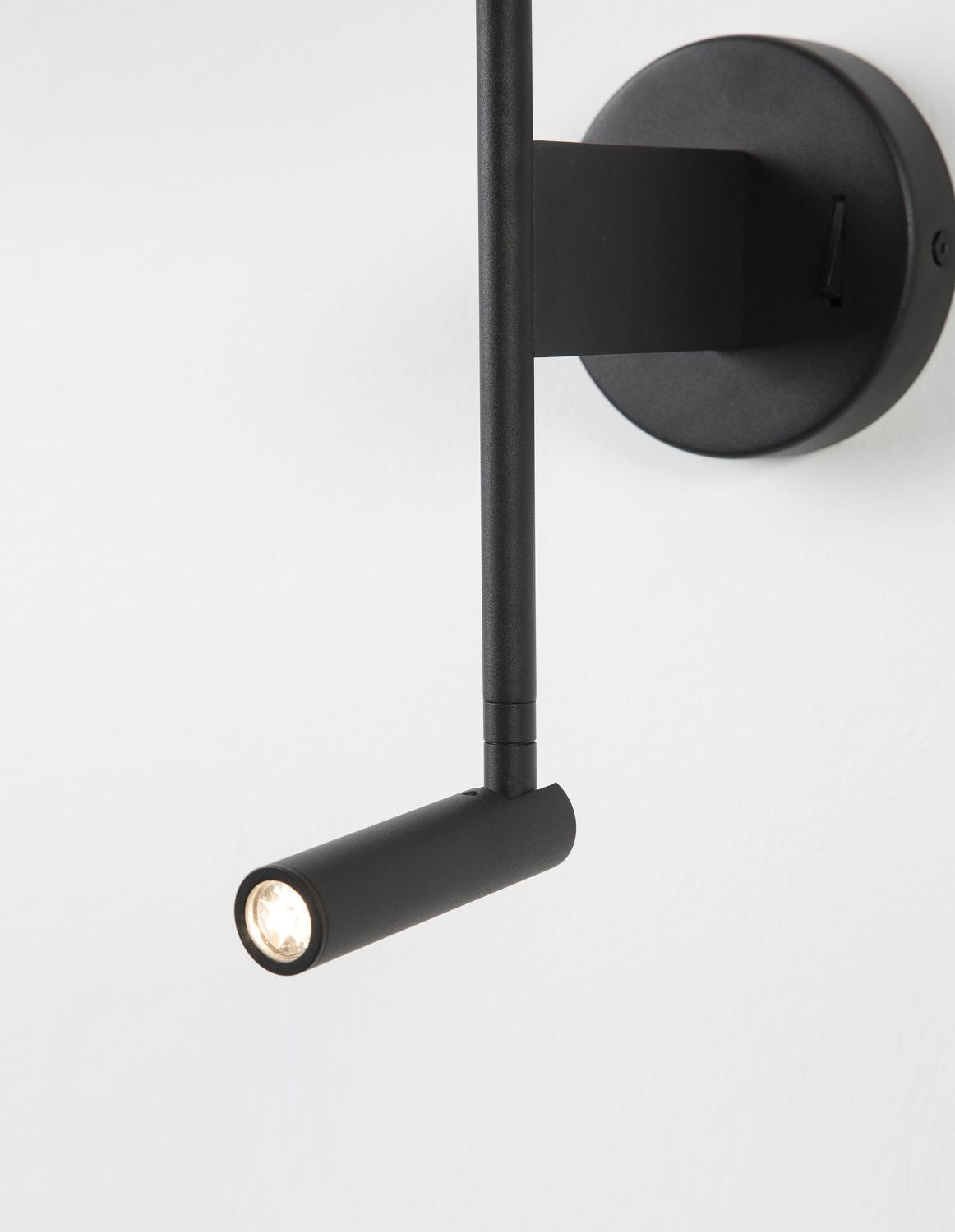Détail du spot de lecture orientable en métal noir avec LED allumée