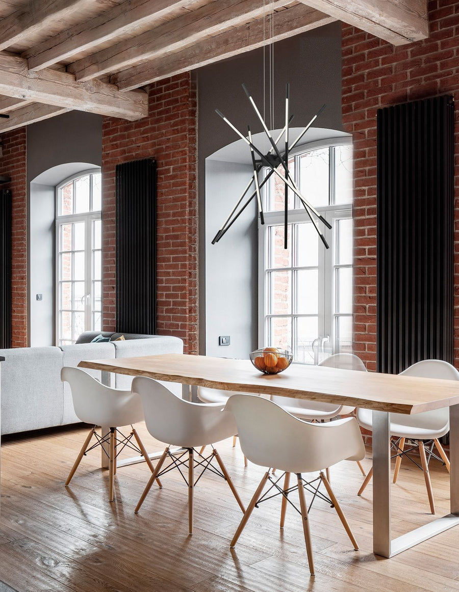 Suspension étoilée noire installée au-dessus d'une table dans un loft en briques rouges.