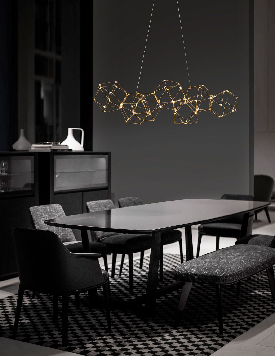 Suspension dorée géométrique suspendue au-dessus d'une table de salle à manger sombre