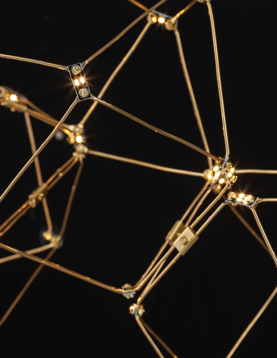Gros plan des LED allumées aux intersections de la structure dorée sur fond noir