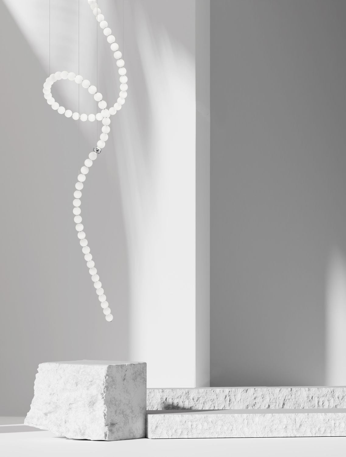 Suspension décorative en perles de verre blanches suspendue dans un intérieur minimaliste avec blocs de pierre
