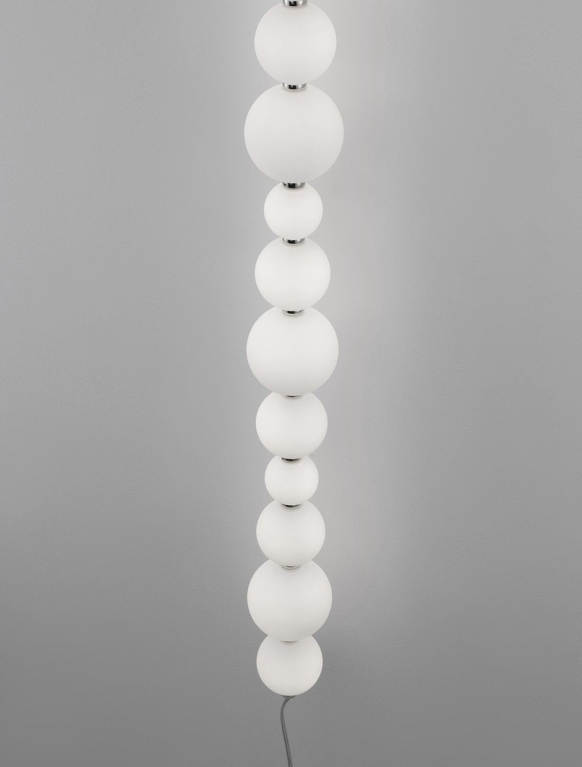 Détail rapproché des boules de verre blanches alternées et des jonctions chromées de l'applique.