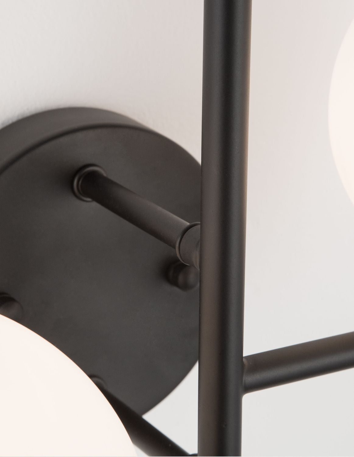 Détail de la platine ronde noire fixée au mur et de son raccord
