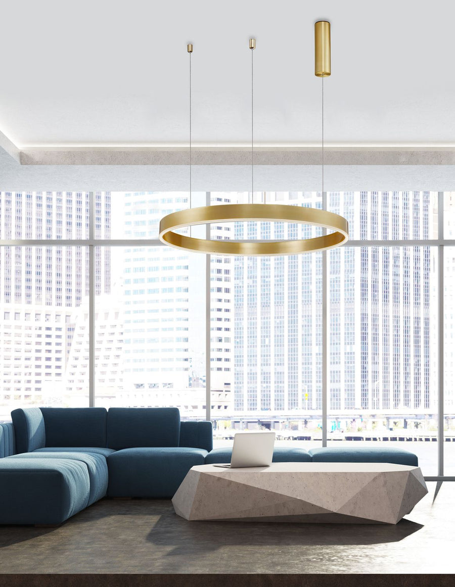 Suspension anneau en laiton éclairée dans un séjour urbain, canapé bleu et baies vitrées.