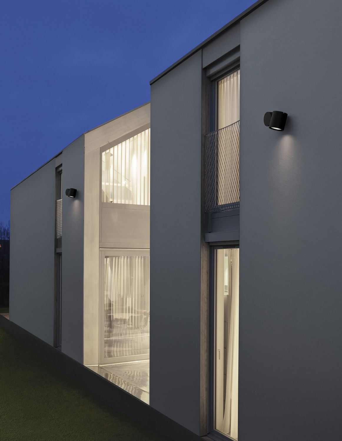 Mise en ambiance nocturne d'une façade moderne avec deux appliques noires allumées