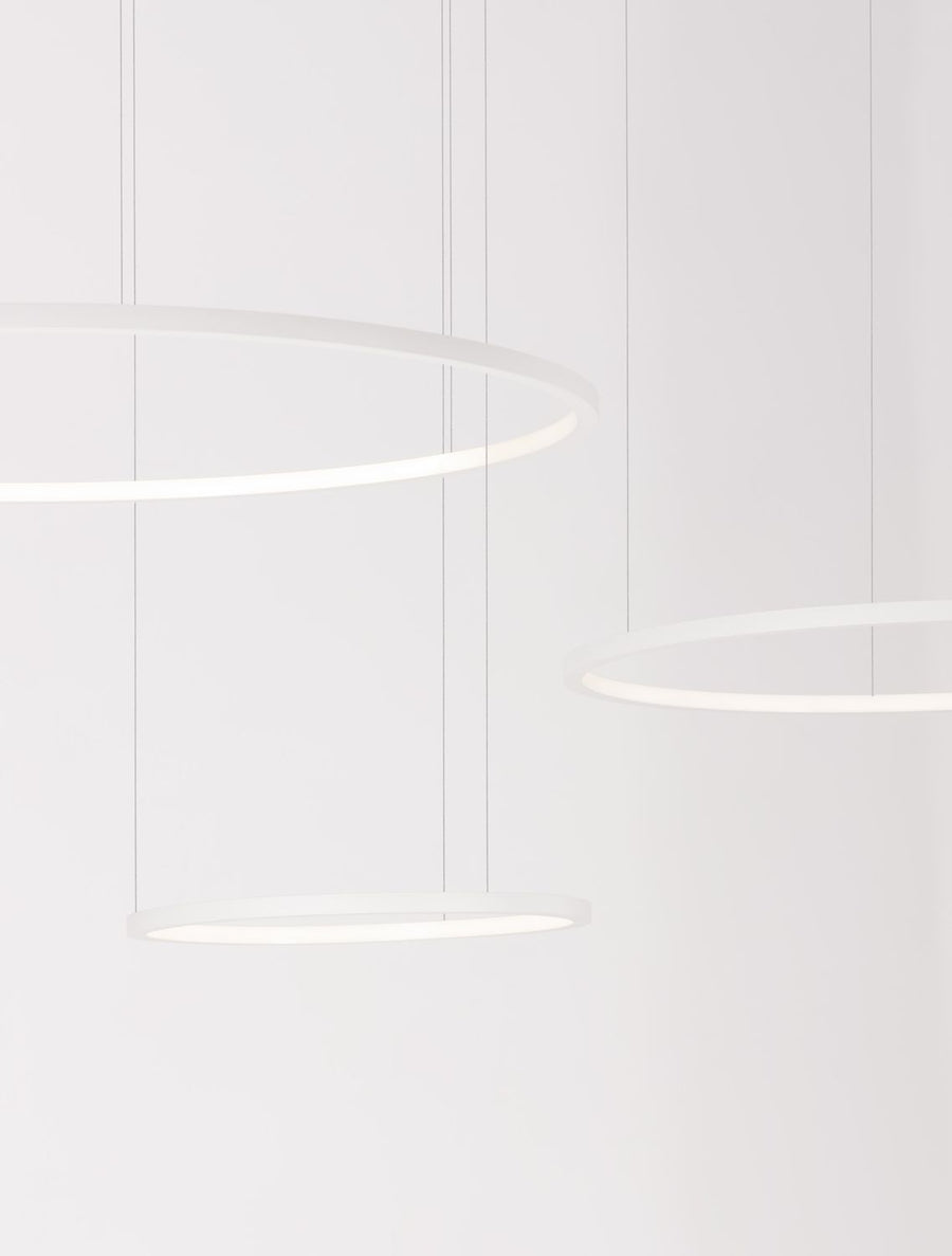 Suspension blanche composée de trois anneaux lumineux ronds suspendus à des câbles, vue rapprochée.
