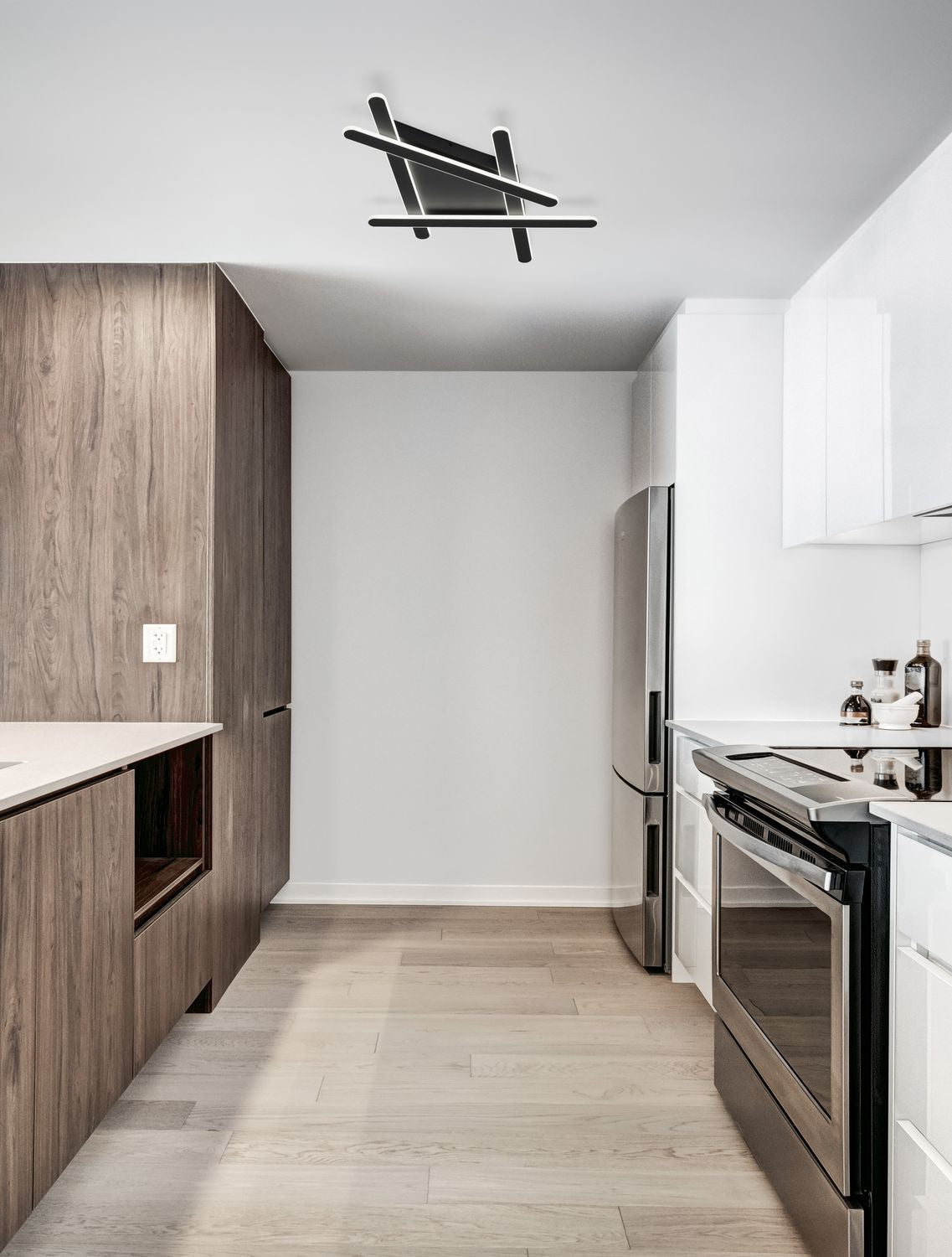 Plafonnier noir allumé fixé au plafond d'une cuisine moderne bois et blanc