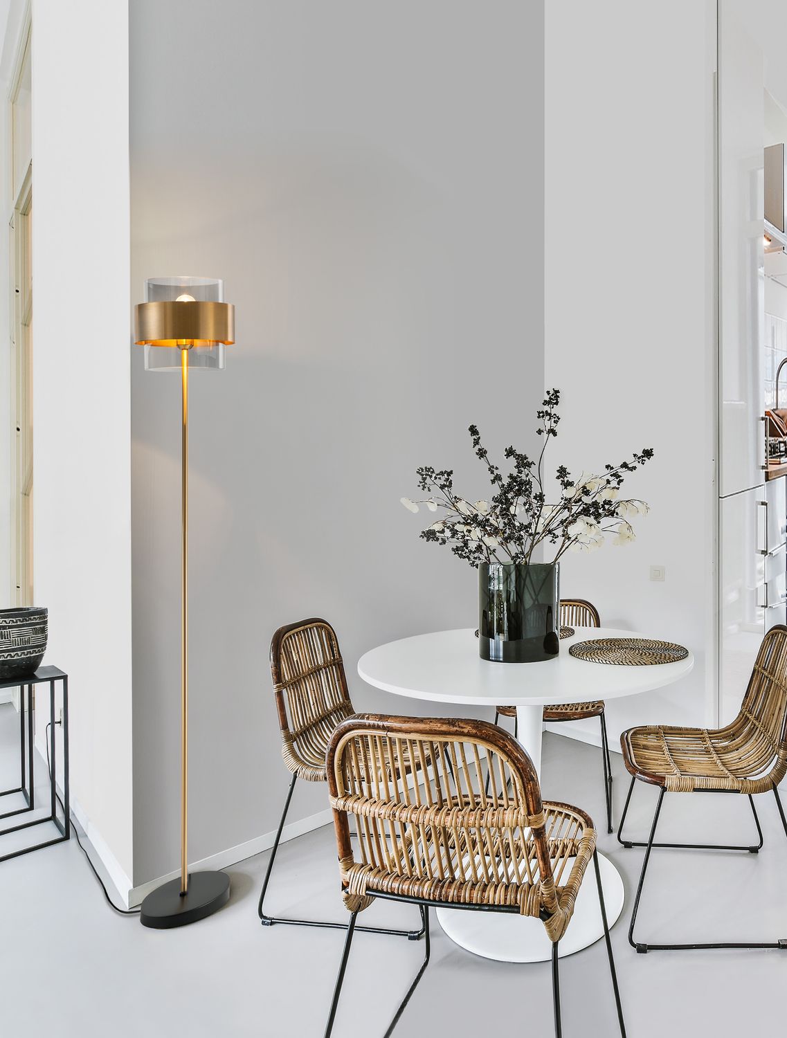 Lampadaire doré installé près d'une table blanche dans un intérieur contemporain clair