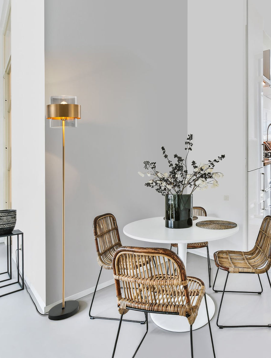 Lampadaire doré installé près d'une table blanche dans un intérieur contemporain clair