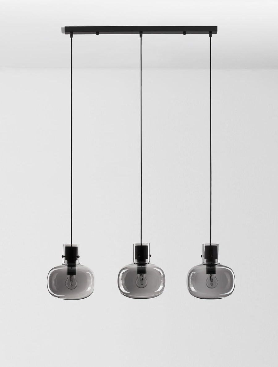 Vue de face du luminaire complet montrant barre noire, câbles et globes fumés