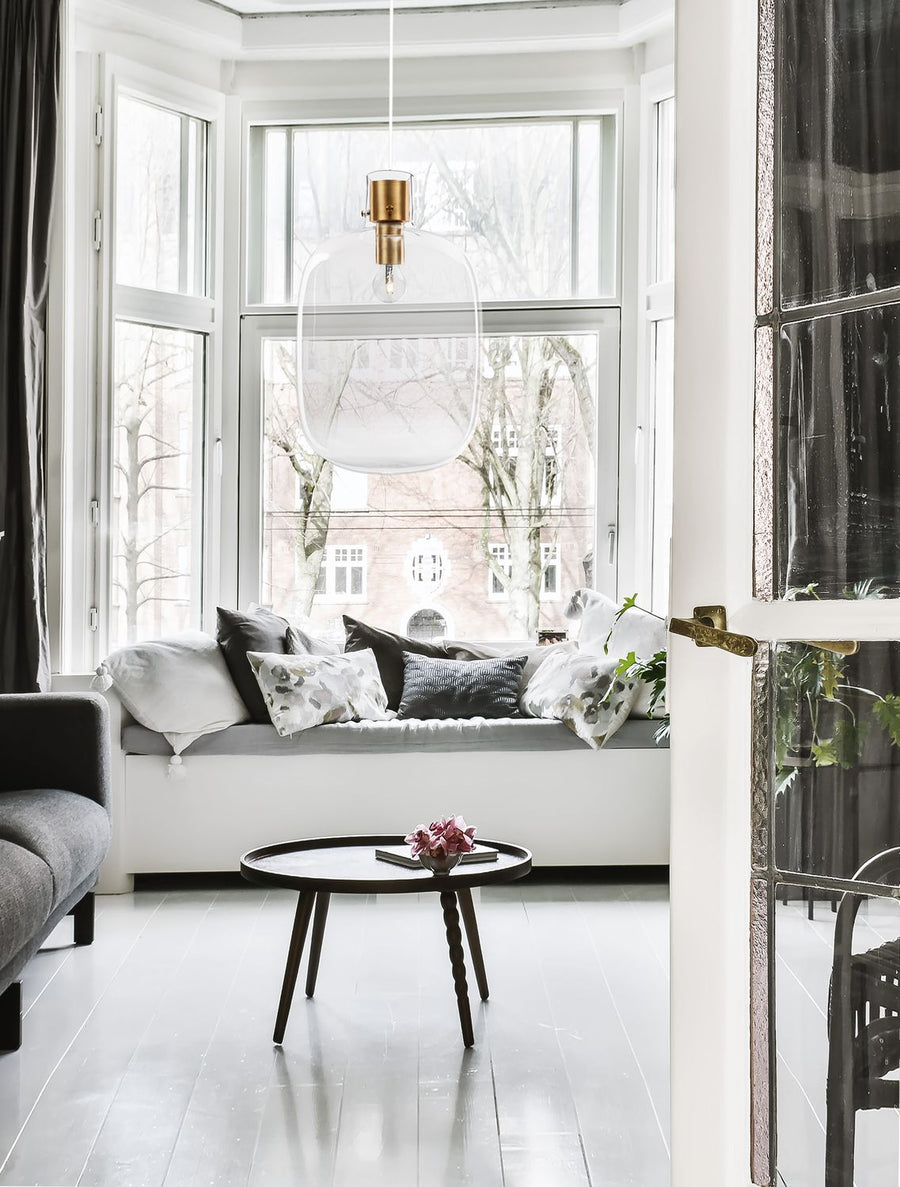 Suspension en verre transparent éclairée devant une grande fenêtre, dans un intérieur très lumineux