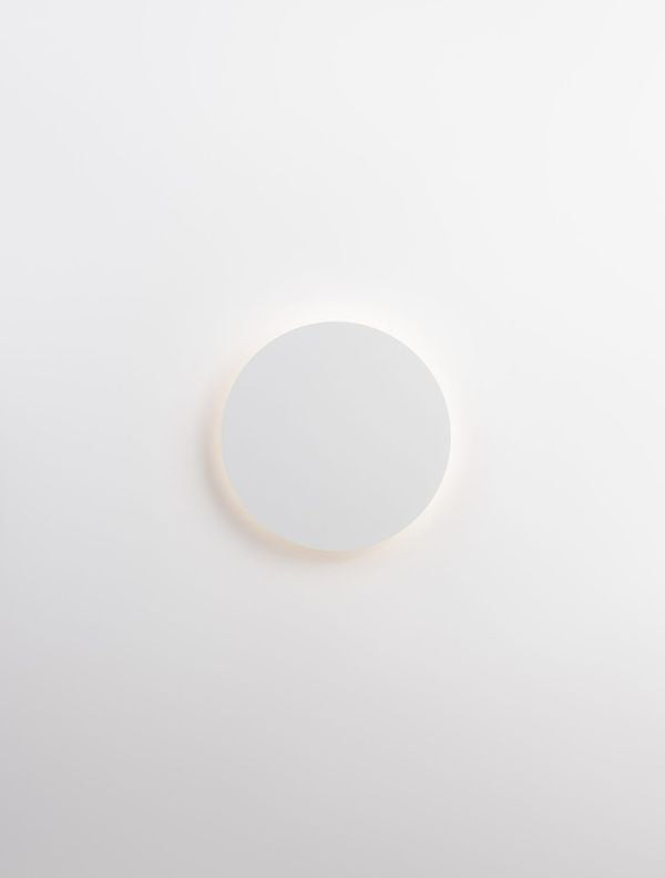 Applique allumée diffusant un halo lumineux chaud sur le mur