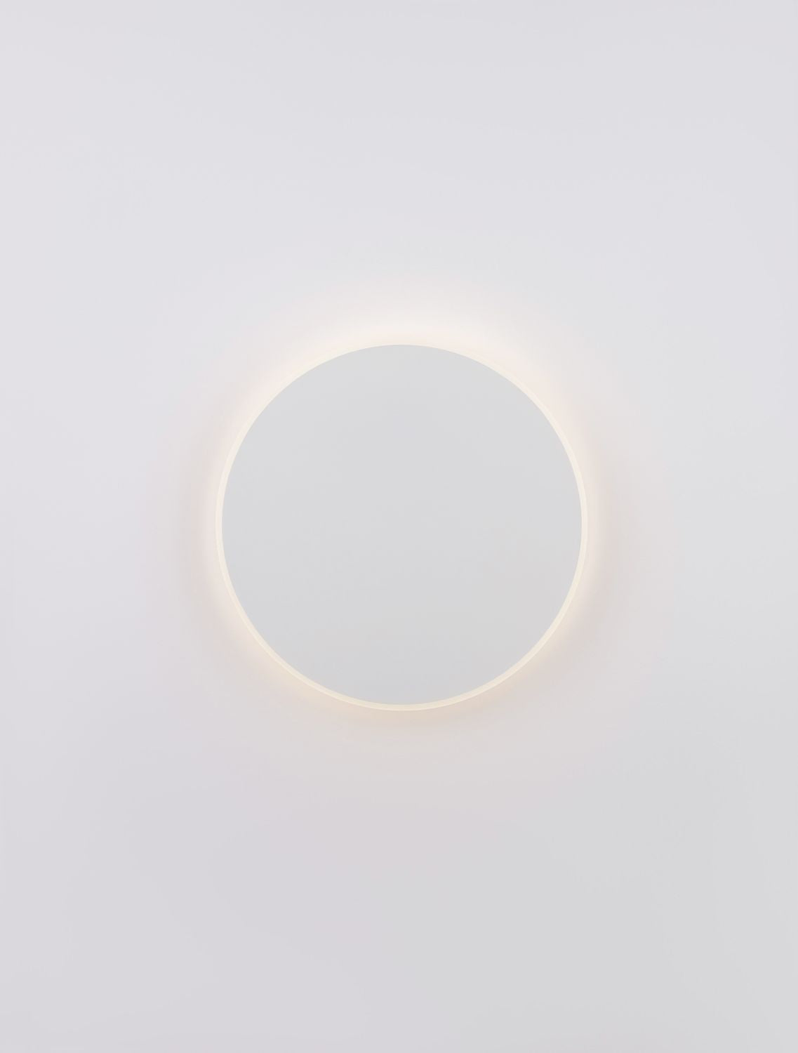 Applique ronde blanche éclairée de face, auréole chaude autour du disque