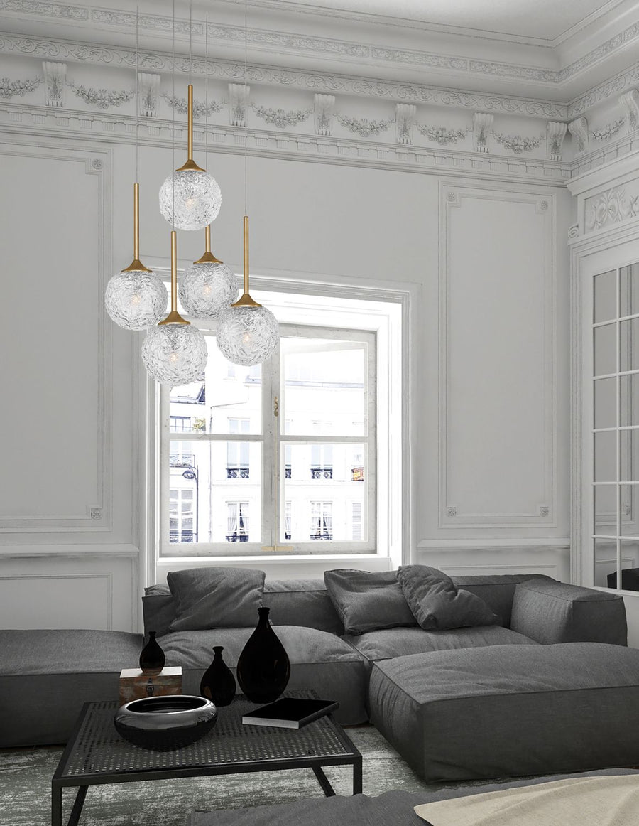 Suspension cinq globes de verre texturé dans un salon haussmannien aux moulures blanches