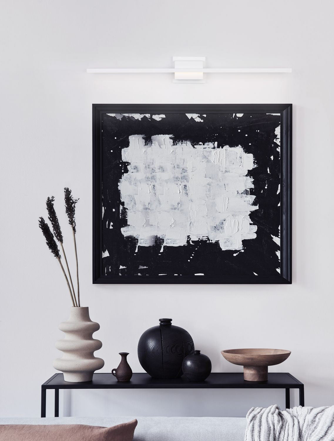 Applique murale blanche allumée au-dessus d'un tableau abstrait noir et blanc