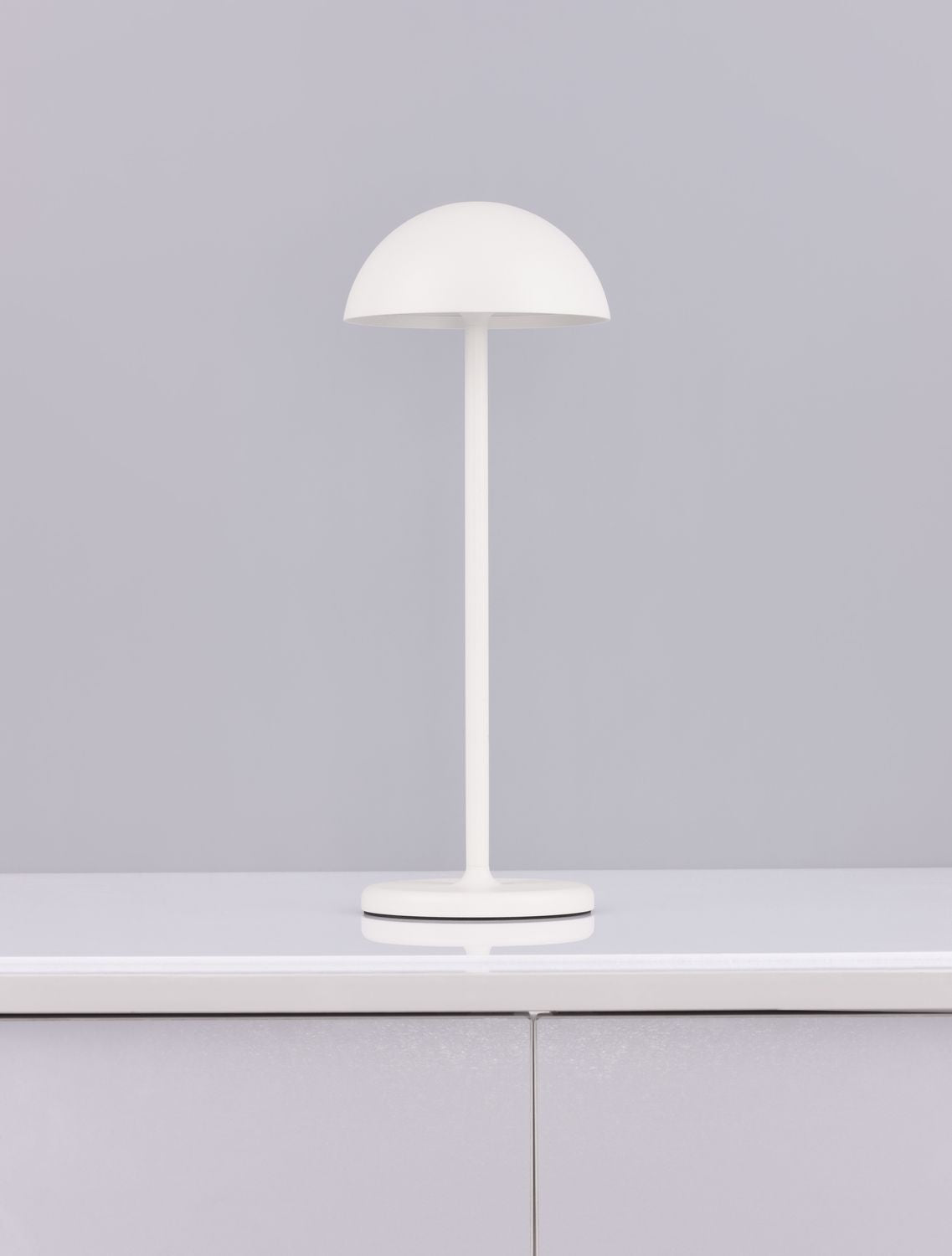 Luminaire blanc posé sur un meuble laqué, vue de face en intérieur