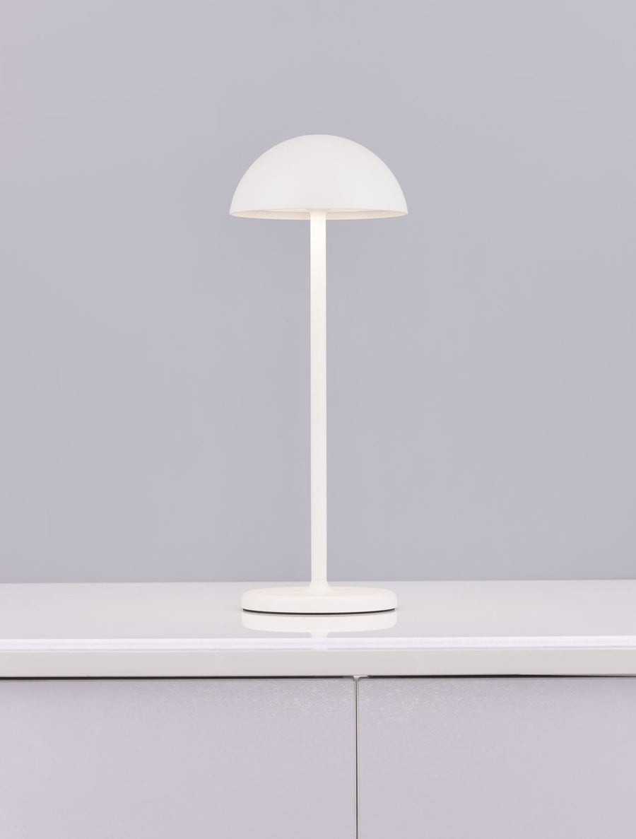 Lampe nomade blanche sur plan de travail gris, reflet sur la surface