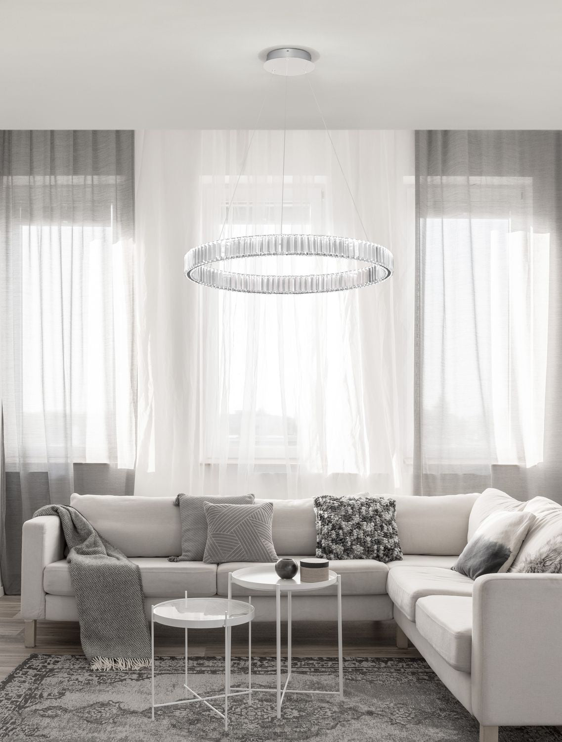 Suspension anneau cristal allumée au-dessus d'un canapé dans un salon clair