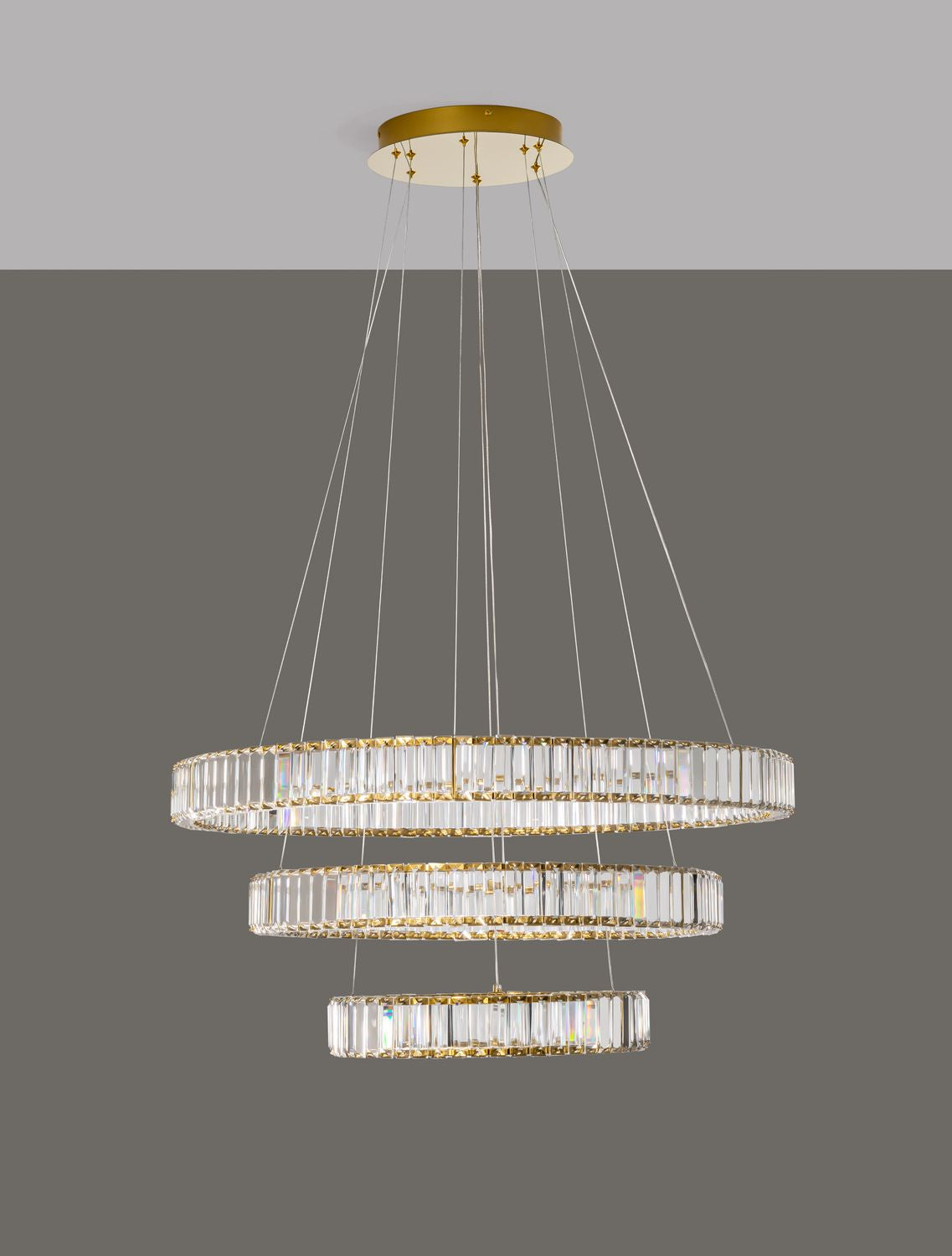Luminaire allumé sur fond gris, câbles et rosace dorée bien visibles