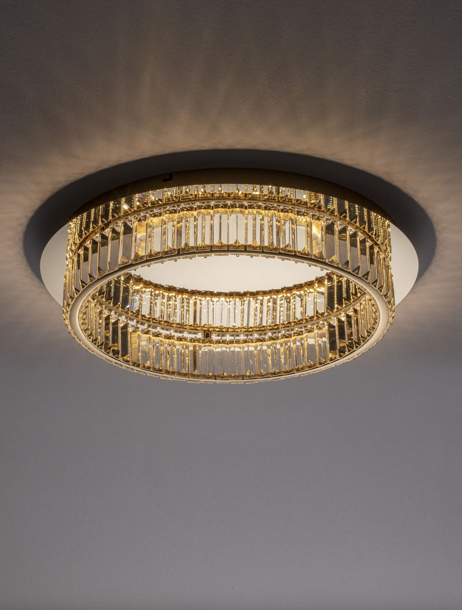 Plafonnier doré et cristal allumé au plafond, vue en contre-plongée dans une pièce sombre