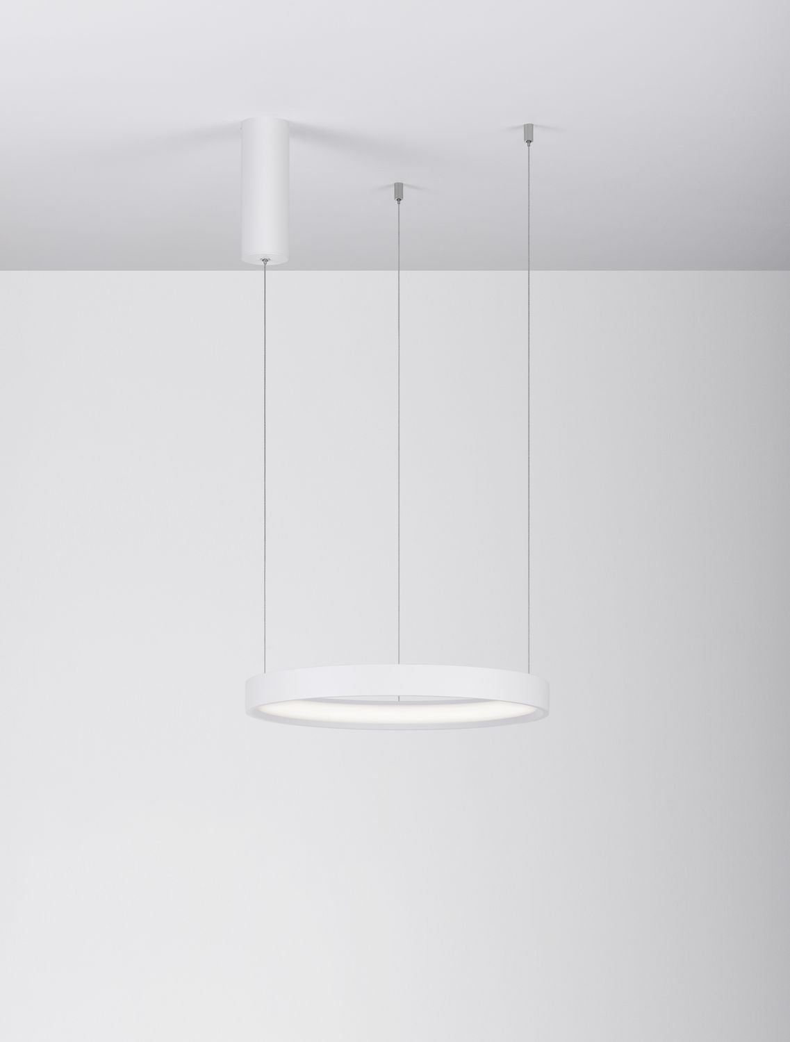 Vue de face du luminaire suspendu, anneau blanc éclairé sous plafond neutre