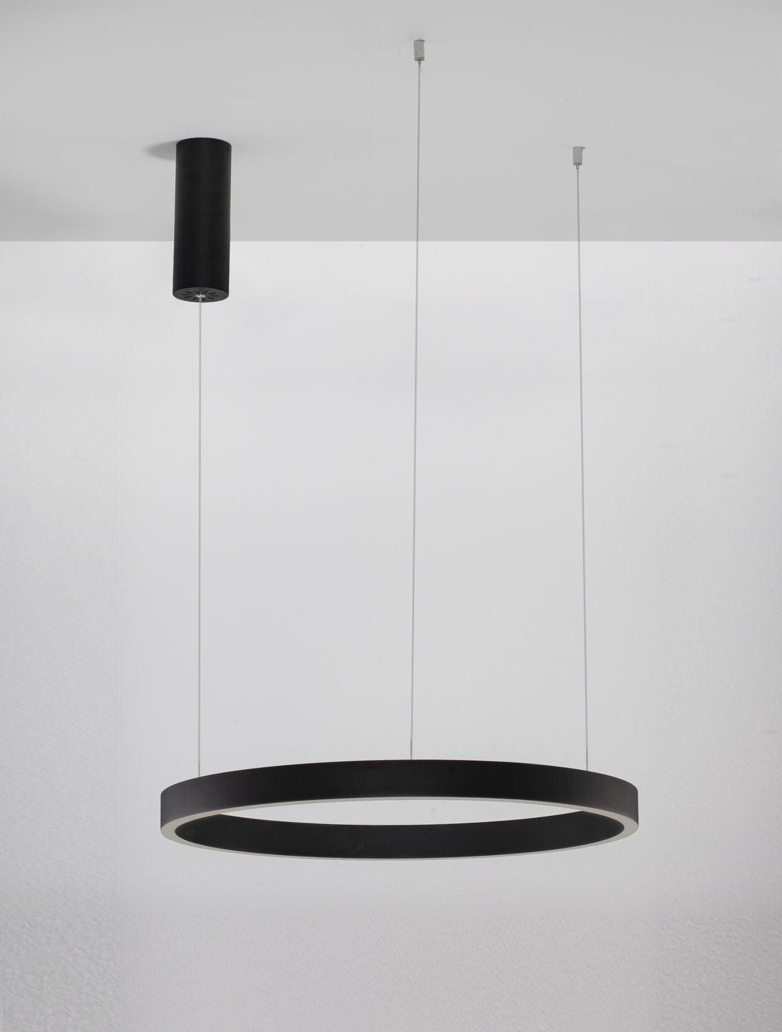 Luminaire installé sous un plafond blanc, anneau noir allumé et câbles fins visibles