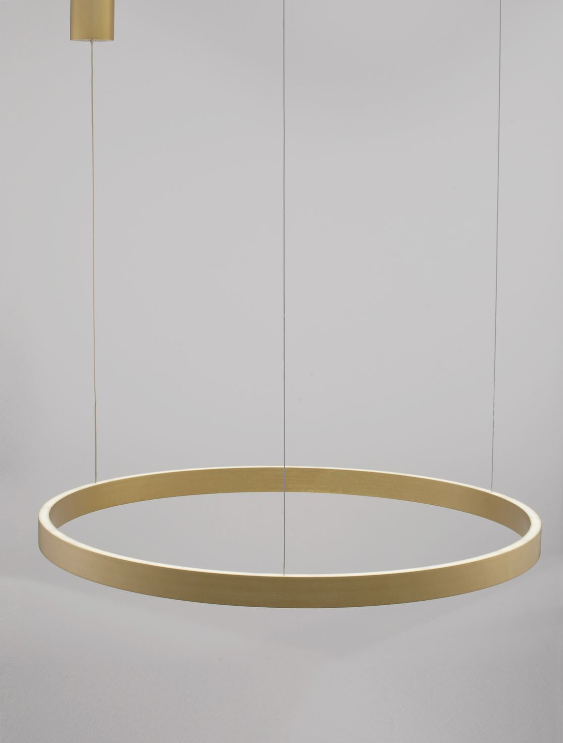 Vue de face du luminaire doré suspendu, anneau circulaire fin sur fond gris clair