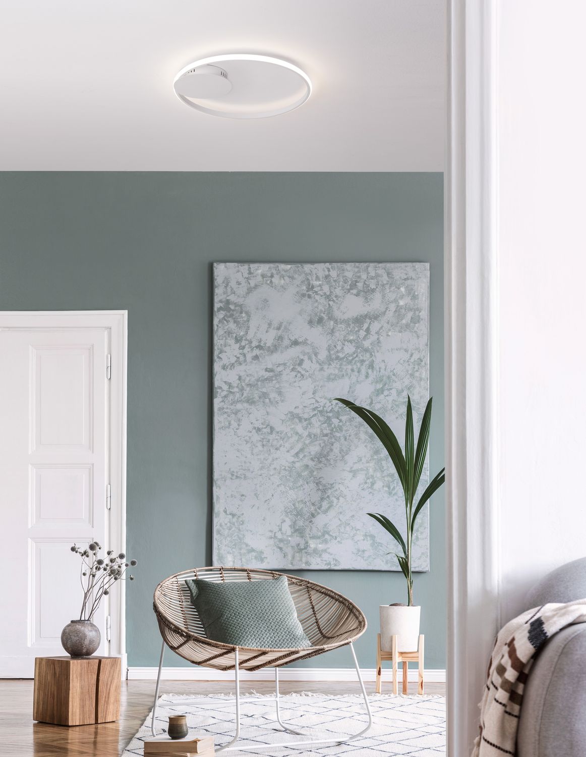 Plafonnier blanc allumé au plafond dans un salon au mur vert et fauteuil