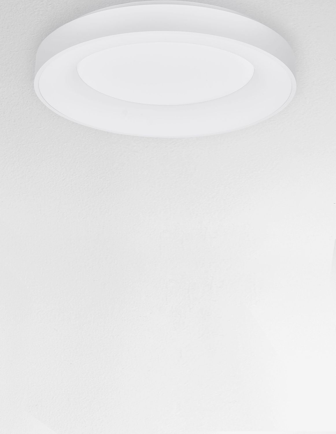 Luminaire blanc installé au plafond vu de dessous dans pièce claire
