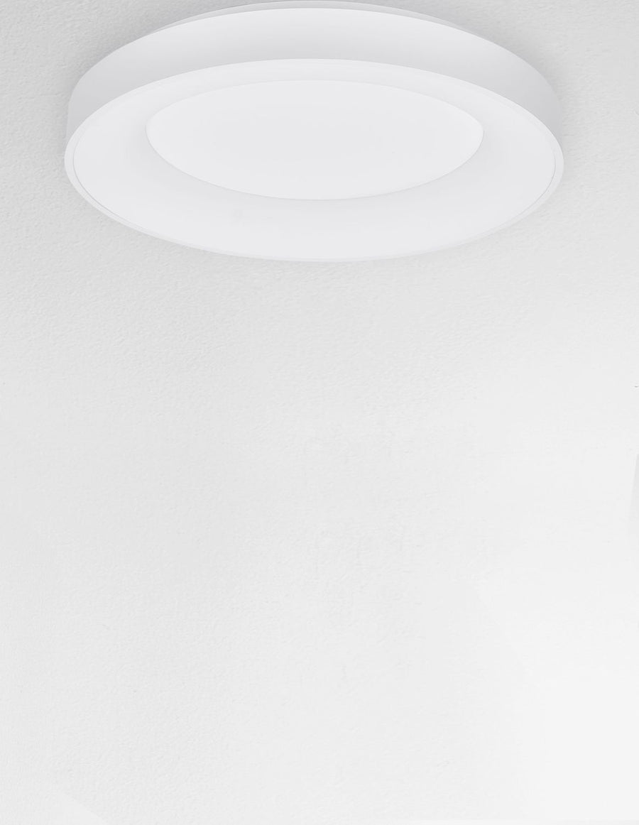 Luminaire blanc installé au plafond vu de dessous dans pièce claire