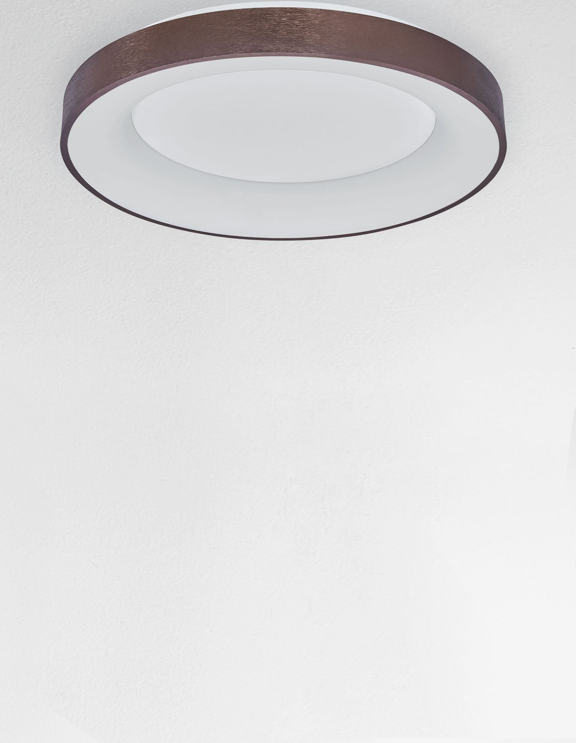 Luminaire vu de biais sous un plafond blanc, anneau brun apparent