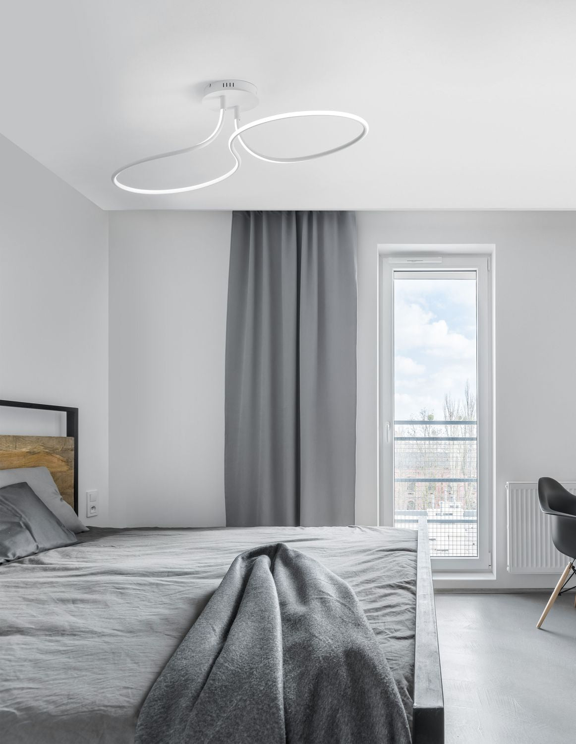 Plafonnier blanc à deux boucles entrelacées installé au plafond d'une chambre grise