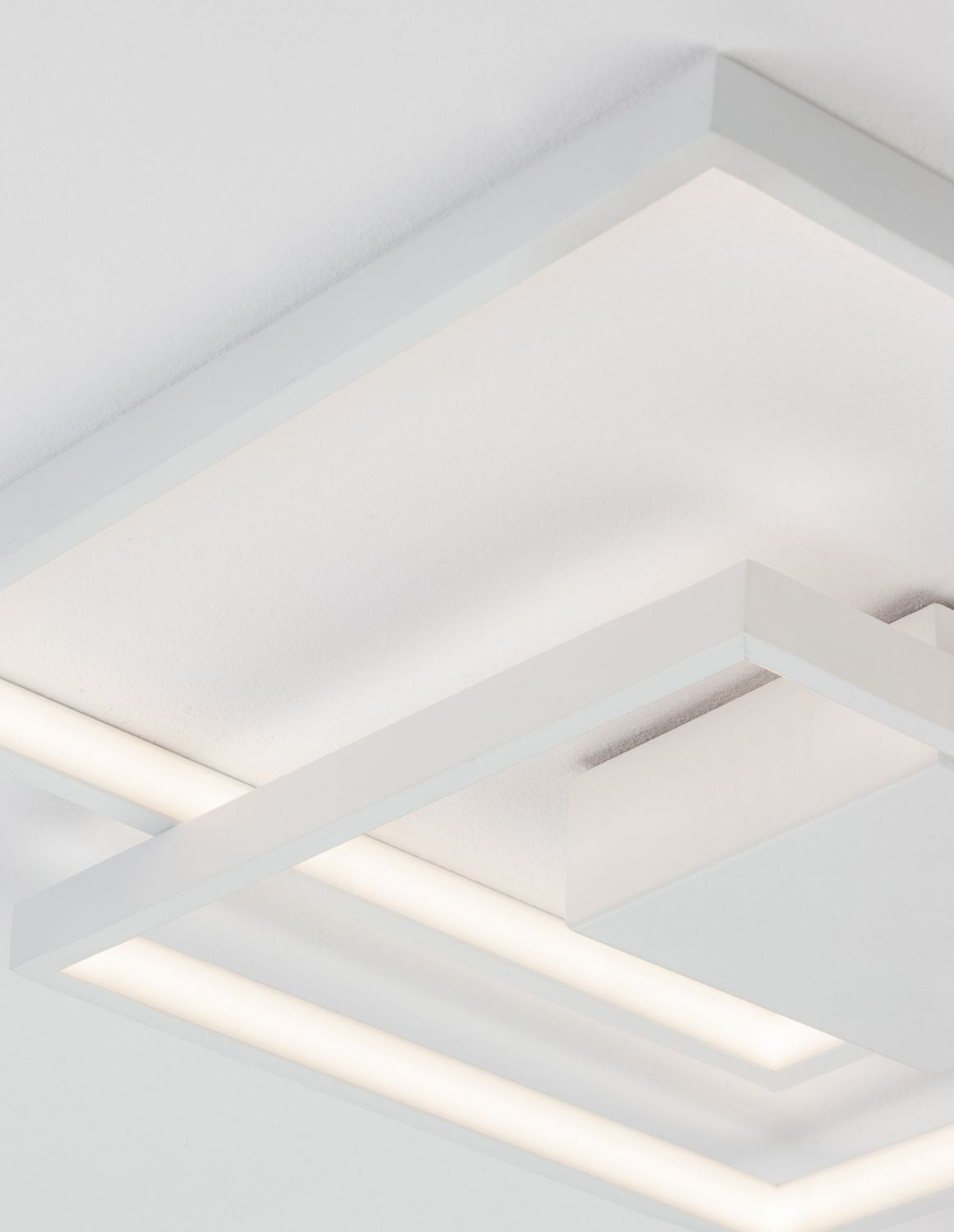 Gros plan sur la lumière LED diffusée sous les cadres blancs du plafonnier