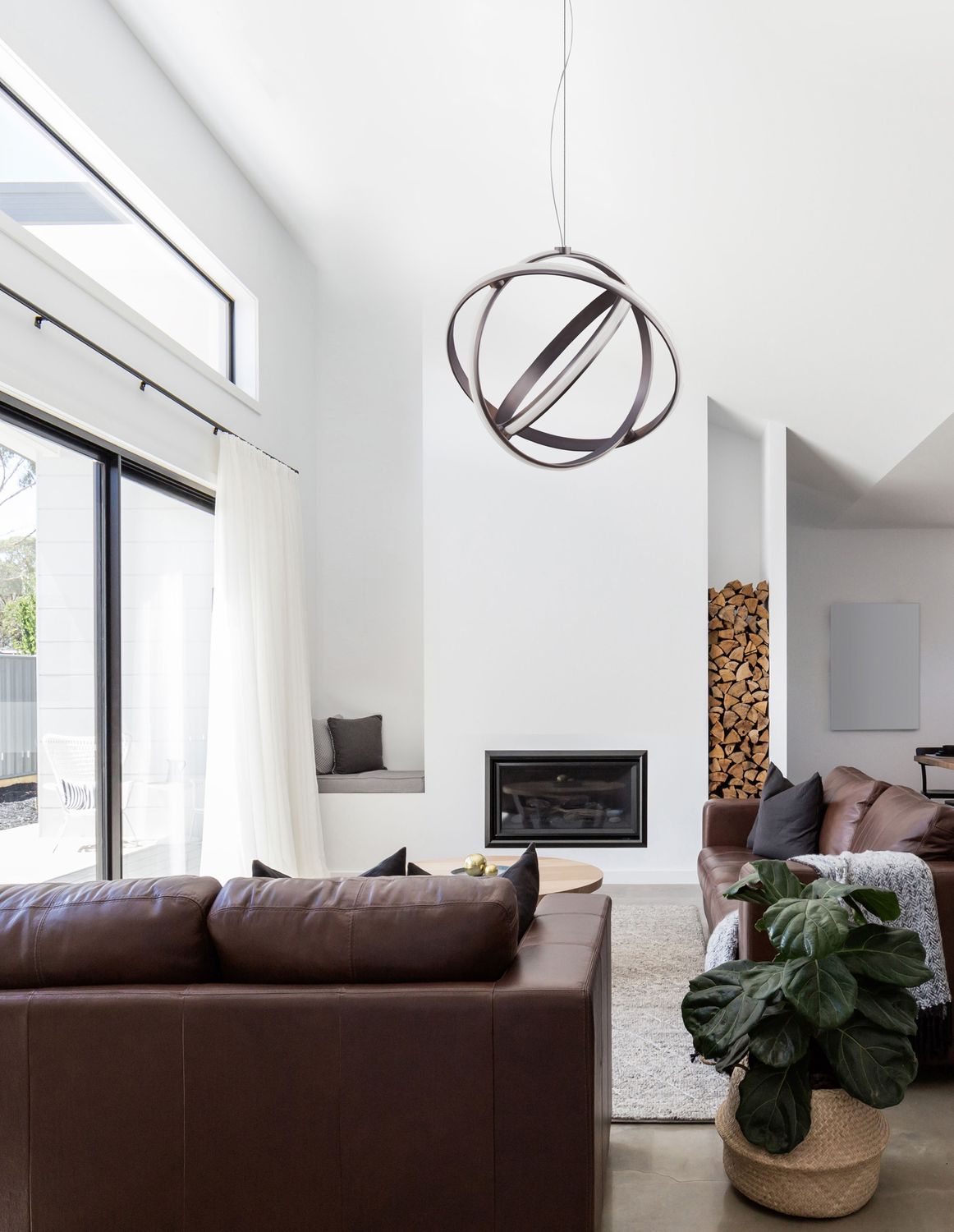 Suspension noire en anneaux entrelacés éclairant un salon contemporain avec canapé en cuir.