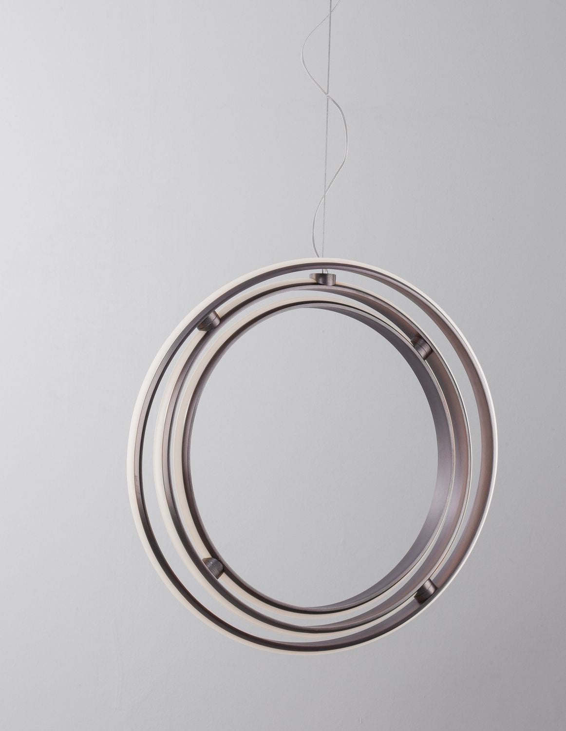 Vue du dessous ou de face des anneaux concentriques du luminaire suspendu sur fond clair.