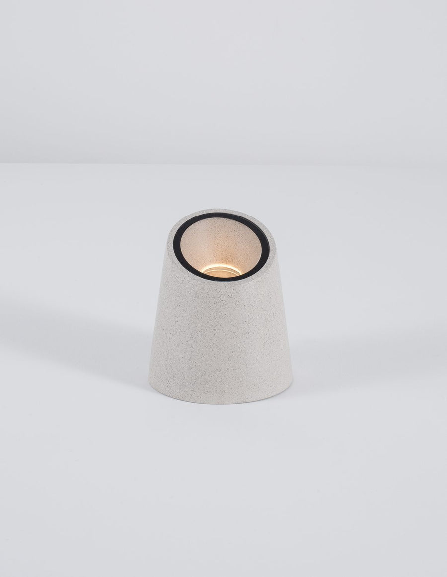 Borne blanche allumée sur fond blanc, diffusant une lumière chaude