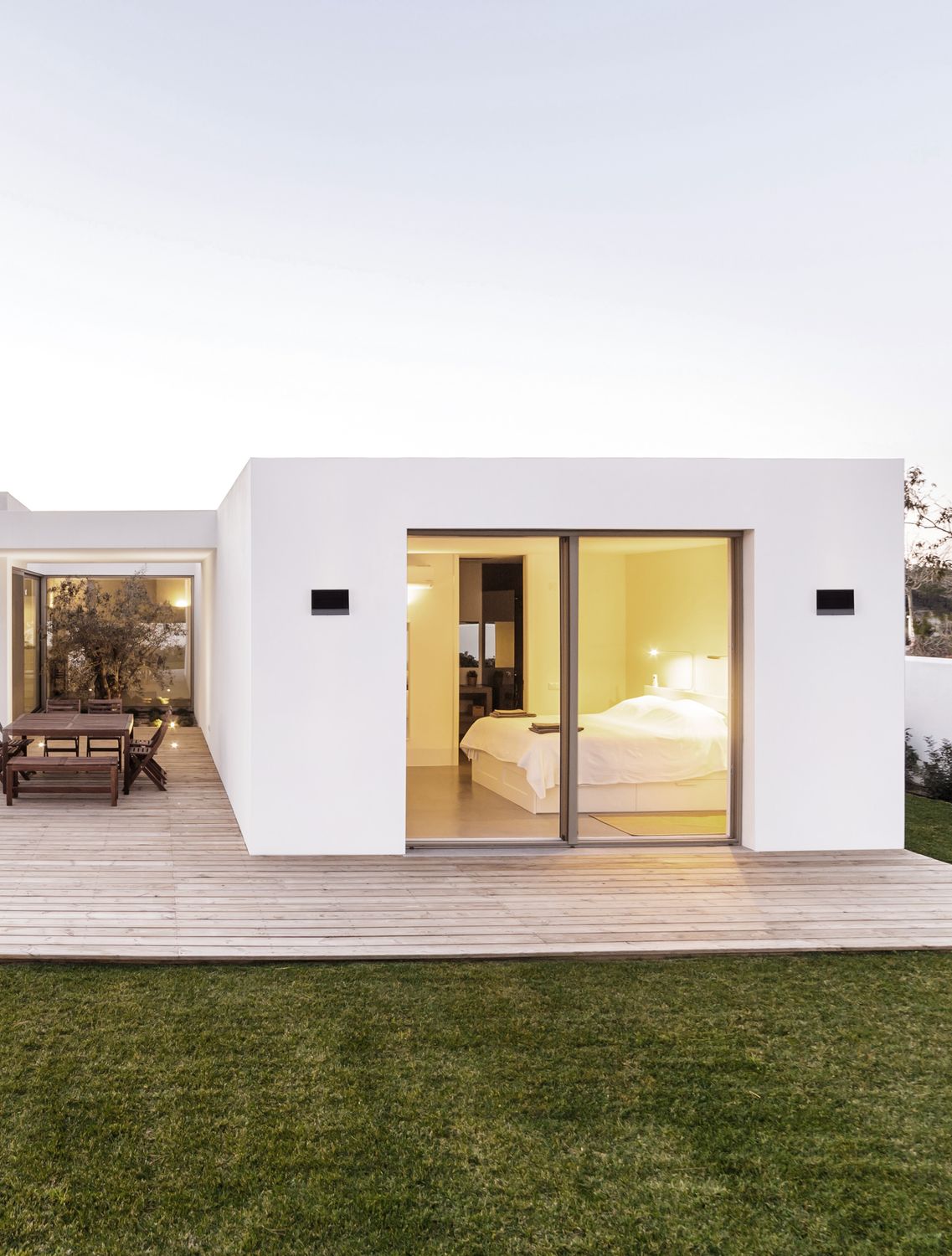 Applique extérieure anthracite fixée sur une façade blanche, terrasse en bois au crépuscule