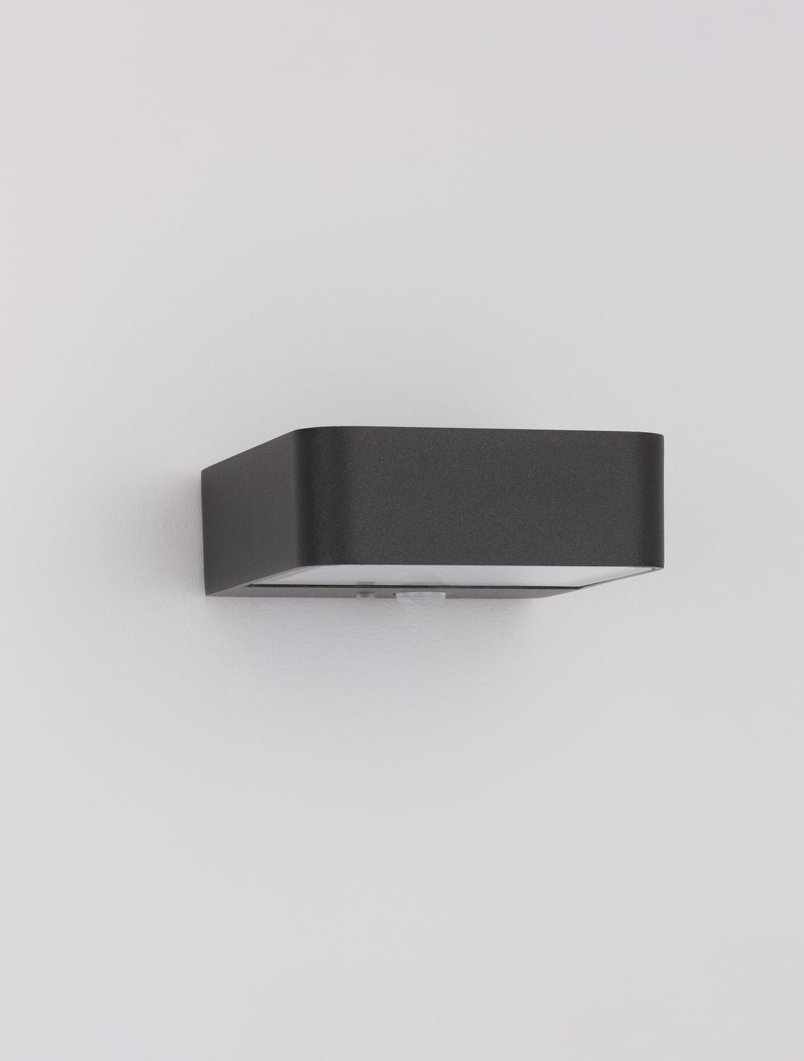Vue de trois quarts du luminaire mural anthracite sur fond gris clair
